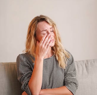 a woman sitting on a couch with her hands on her face