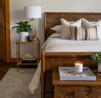 A thoughtfully styled bedroom with a wooden bed frame, a gold-accented bedside table, an area ru