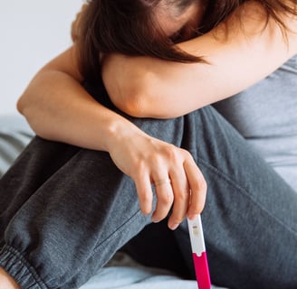 a woman sitting on a bed with a pregnancy test in her hand