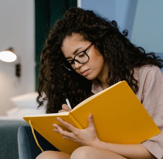 a woman sitting on a couch with a notebook and pen