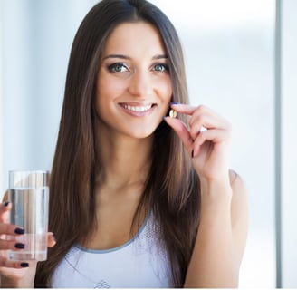 a woman holding a glass of water and a pill pill