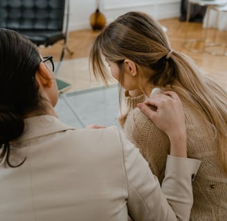 a woman in a beige jacket is sitting on a couch