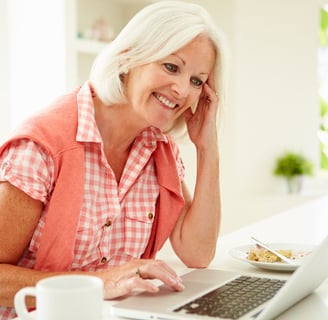 a woman sitting at a table with a laptop computer