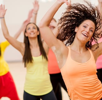 a woman in a bright orange tank top and black pants