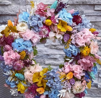 a wreath of flowers on a chair in front of a brick wall