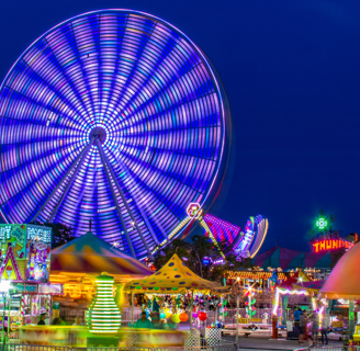 a ferris wheel at night time with people walking around