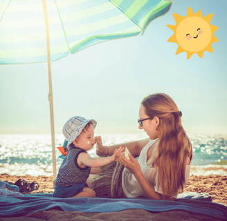 a woman sitting on a blanket with her baby near seaside