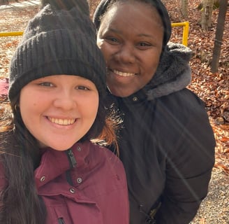 two women standing next to each other. one is in a burgundy jacket and the other is in a black one. 
