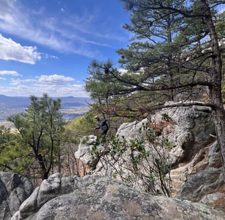 a person's feet in the air with a person standing on a rock