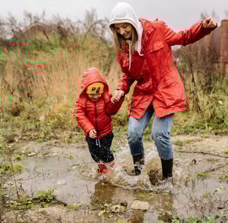 woman splashing in puddles with child