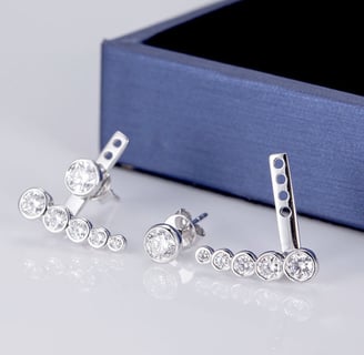 The image showcases a modern and elegant pair of silver or white gold ear climber earrings, featurin