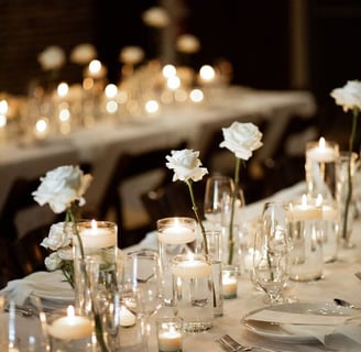 Mesas para evento decorada con manteles, llena de platos, tenedores, y otra decoracion