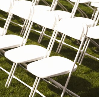 Sillas blancas plegables para eventos al aire libre en el paso