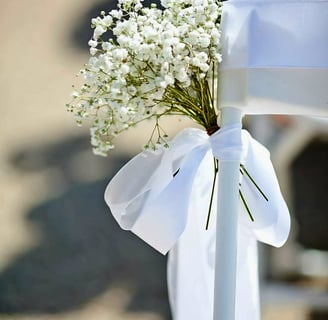 Silla para boda decorada con un liston blanco y flores