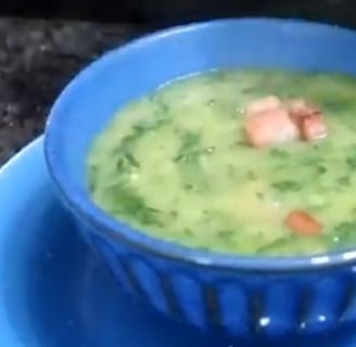 Mingau de couve com bacon, servido em uma tigela azul. O mingau tem uma textura cremosa e homogênea,