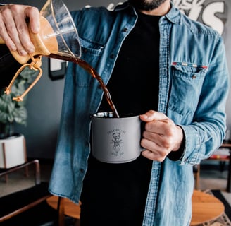 a guy pouring coffee from a chemex into a mug