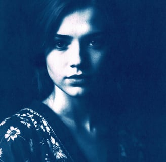 Close-up portrait of a young woman with fair skin, long straight hair, and soft lighting highlightin