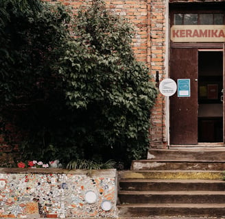 Old red brick house with open doors. On top of it is written: ceramics. 