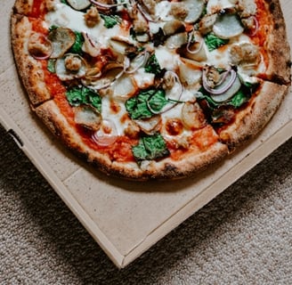 a pizza in a box with cheese and spinach. Learn more about food addiction and gluttony.