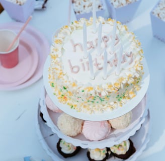 a cake with candles and cupcakes on a table