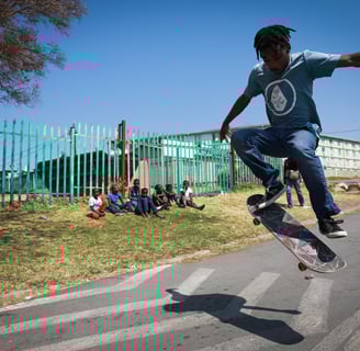 a man in a blue shirt is doing a trick on a skateboard