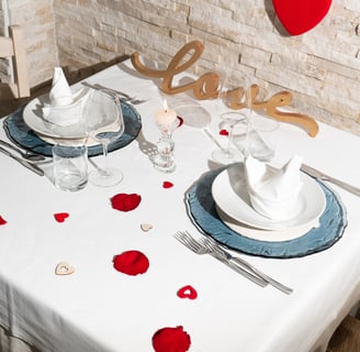 tavolo di ristorante elegantemente e romanticamente apparecchiato con petali di rose