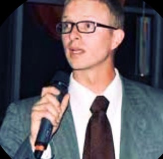 Tomkins wearing a suit and giving a speech during a rally in Boise Idaho.