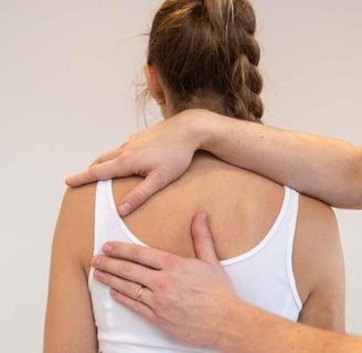 een vrouw met een witte tank top met 2 handen op haar rug.