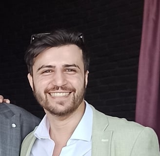 Adem Asha in a suit and tie smiling for the camera