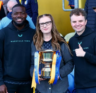 Stags defender Deji Oshilaja receives his SSA Player of the Year Award from Amy Bennett and Daniel Harris.