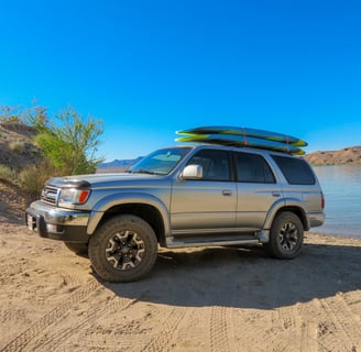 4runner with paddle boards on top next to the river