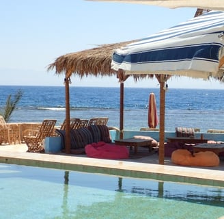 een zwembad op het strand met parasols en stoelen