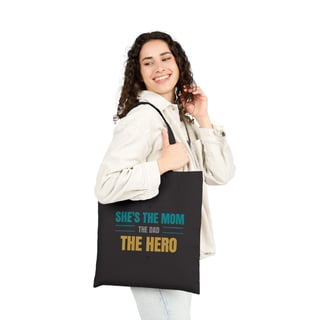 a woman holding a black bag with a message she's the hero