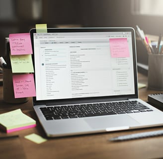 a laptop computer sitting on a desk with sticky notes and sticky notes