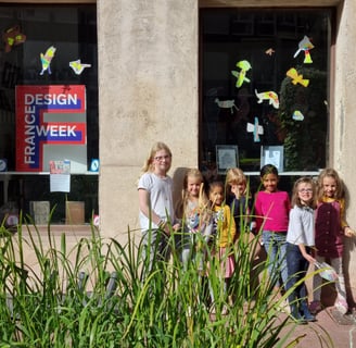 Un groupe de jeunes enfants prennent la pose devant une affiche de la France Design Week
