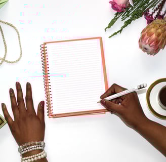 a woman's hands holding a notebook and writing on a notebook