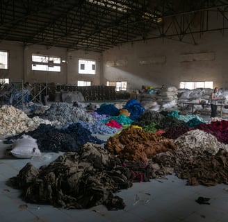 Multiple large color-coded piles of fabric in a warehouse