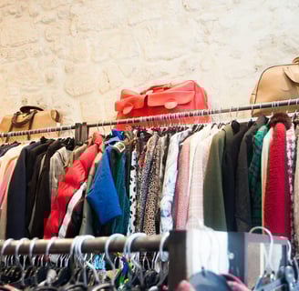 A full rack of long sleeve clothes with purses on top