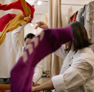 Two people standing with their arms up mid-throw tossing donated clothes into the air
