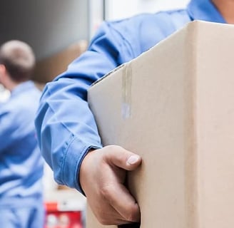 a man in a blue shirt is holding a box of boxes