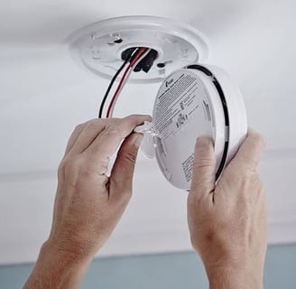 a person is holding a white smoke detector in their hands