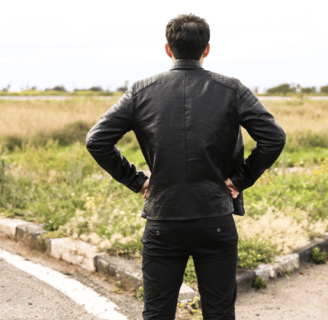 a man in a suit and tie standing on a road