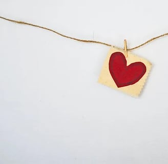 a heart shaped piece of paper with a red heart hanging from a string