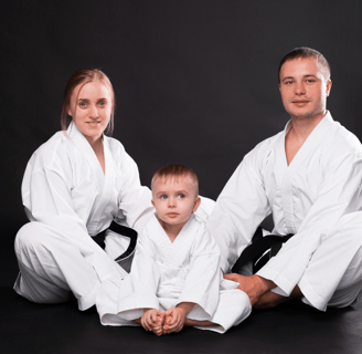 a man and woman in karate gear posing for a family photo