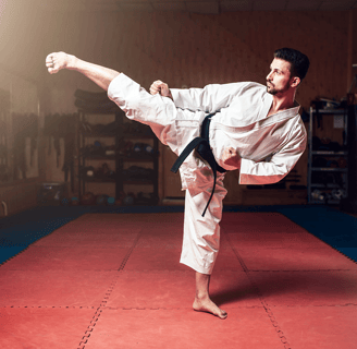 a man in a karate outfit is doing a kick kick - kick