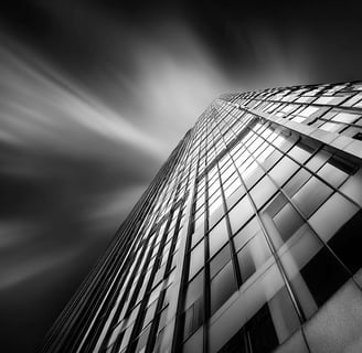 Abstract black and white photo of a glass skyscraper shot from a dramatic upward angle