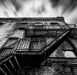 Old brick building with fire escape in motion sky.