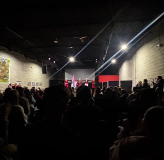 a crowd of people standing in a room with a stage