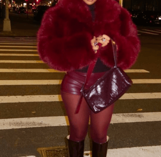 a woman in a red coat and boots is walking across the street