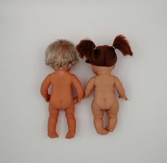 a back view of a Miniland doll next to a Minikane doll